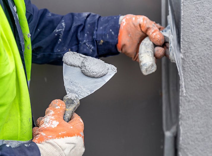 Worker applying plastic cement to wall